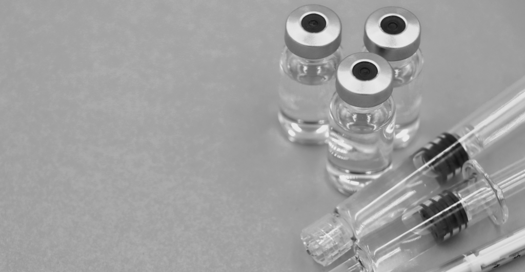 Close-up of vaccine vials and syringes on a blue surface, emphasizing healthcare.